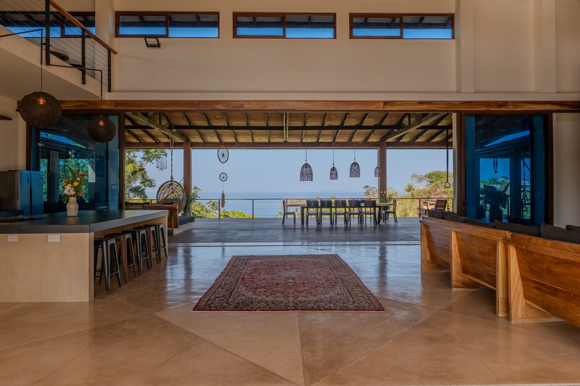 The open great room at Tanit Villa flowing onto the deck and out to the Pacific — the view that greets guests on arrival