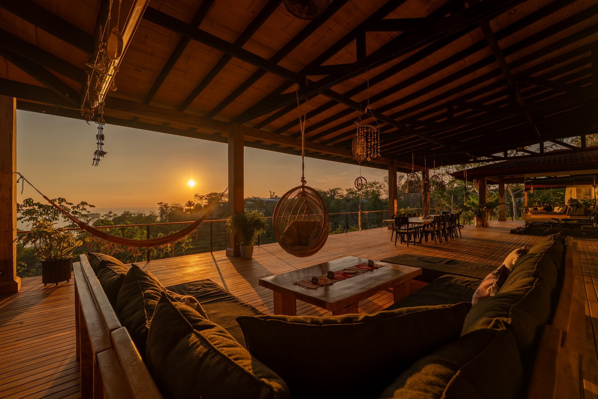 The covered terrace at sunset — hanging chair, lounge and Pacific view
